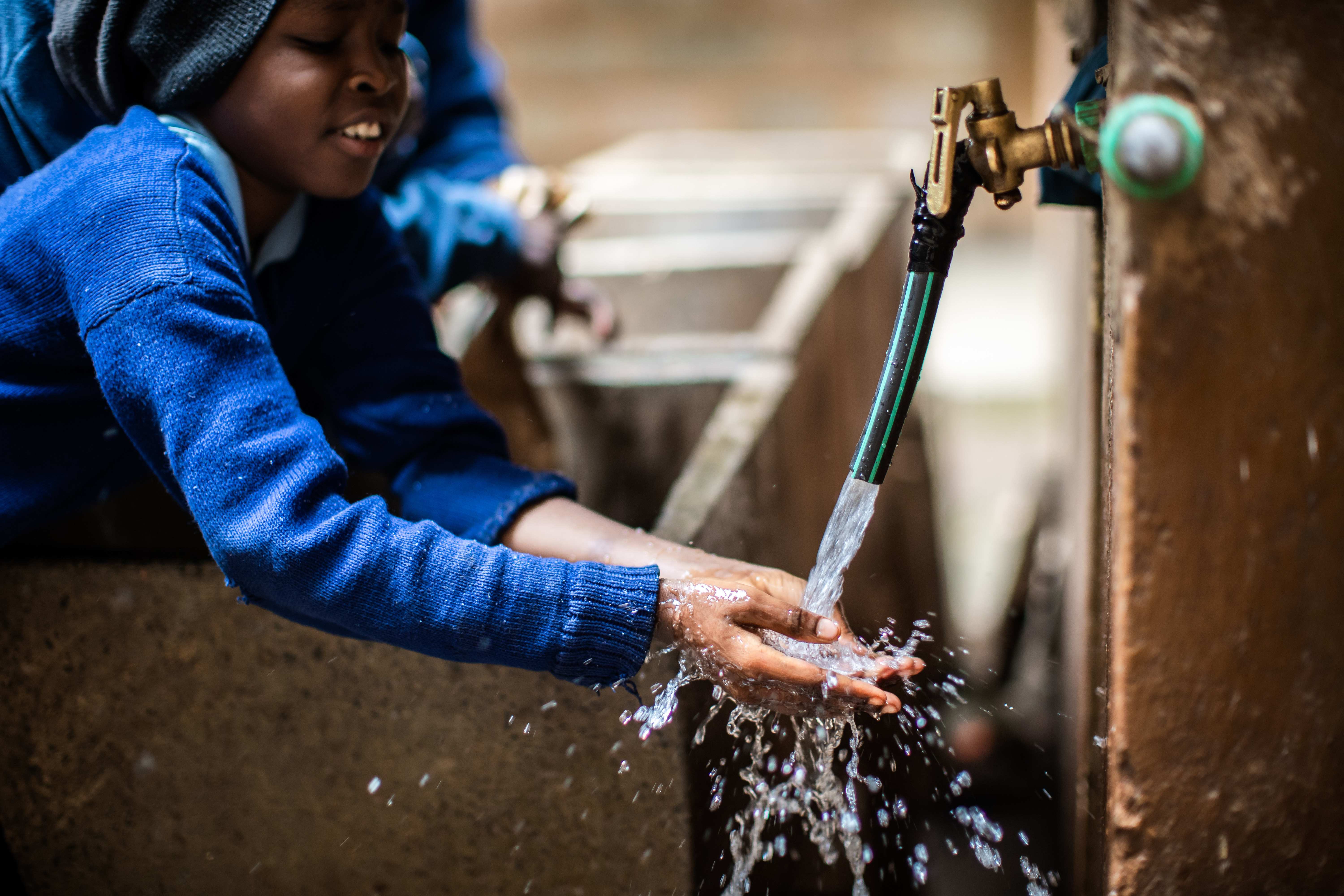 Kind wäscht Hände an Brunnen 