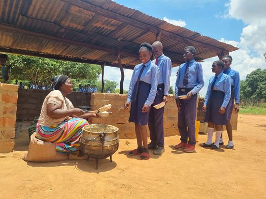 Mweetwa Esther verteilt porridge an die Kinder der Haluumba Primary School (Quelle: Kindernothilfe-Partner)